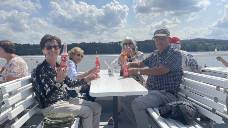 Eine Gruppe von Bewohnerinnen und Bewohnern genießen bei schönem Sommerwetter und mit Getränken eine Schifffahrt auf dem Baldeneysee.
